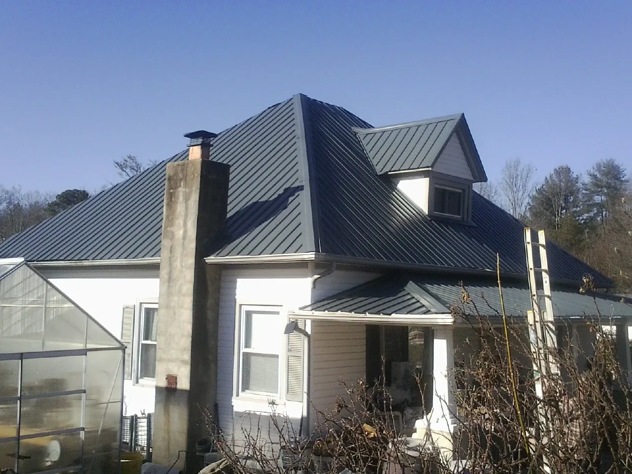 Dark blue standing seam metal roof on a white farmhouse with dormer — Slate & Tile Roof Repair by Roofing Brothers in Wabasha