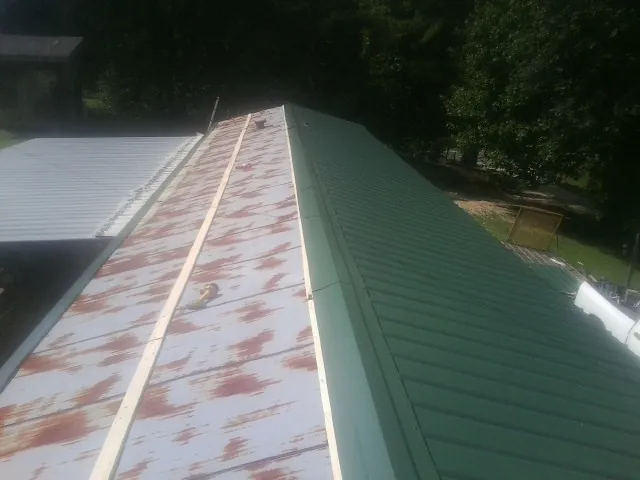 Old rusted panels beside newly installed green metal roofing — Wind Damage Roof Repair by Roofing Brothers in Wabasha