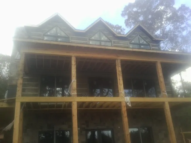 Dormers and porch framing on a large log home under construction — Roof Coating work by our crew in Wabasha
