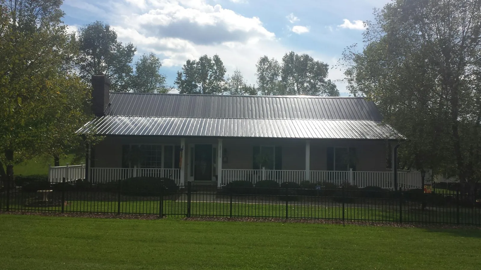 Gray metal roof on a brick ranch with a full width front porch — Gutter Guard Installation work by our crew in Wabasha
