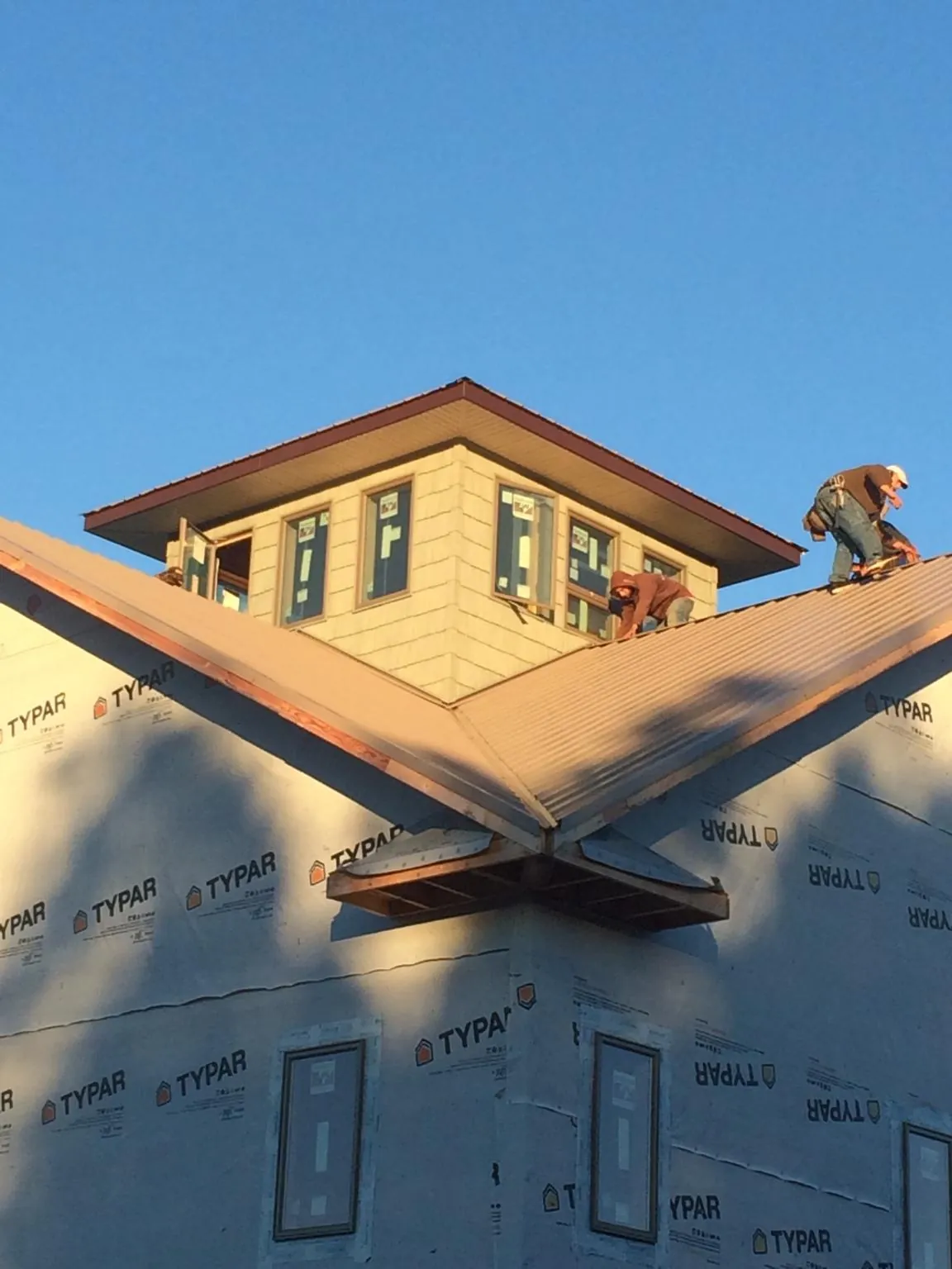 Roofers working around a rooftop cupola on a new metal roof at sunset — Roof Waterproofing in Wabasha by Roofing Brothers
